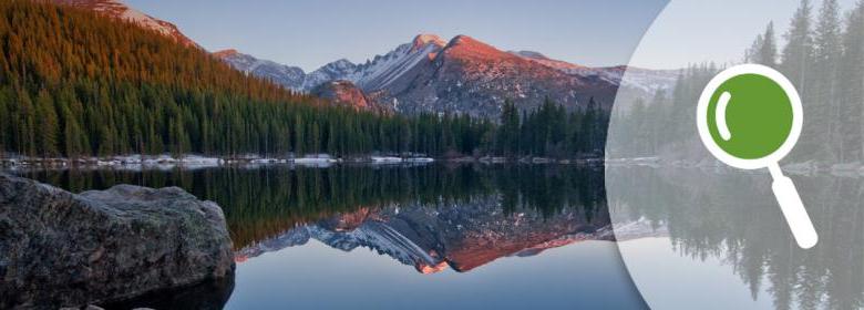 banner of magnifying glass icon over serene mountain lake scene